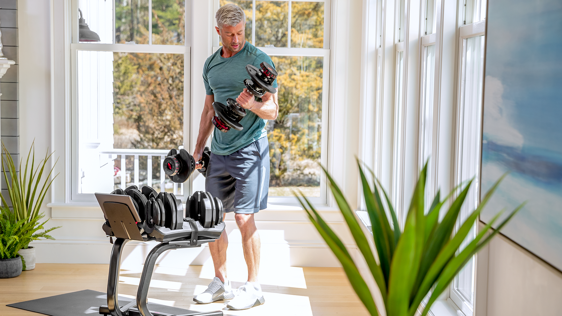 Man using BowFlex SelectTech Dumbbell Stand with Media Rack in home