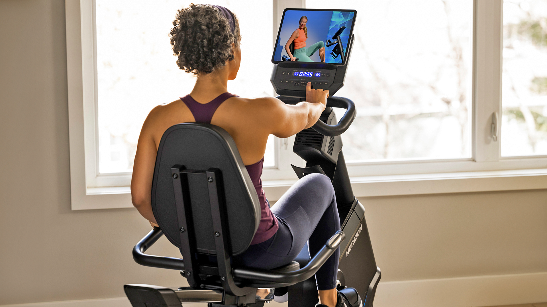 Woman using personal tablet with Horizon 5.0R recumbent bike console