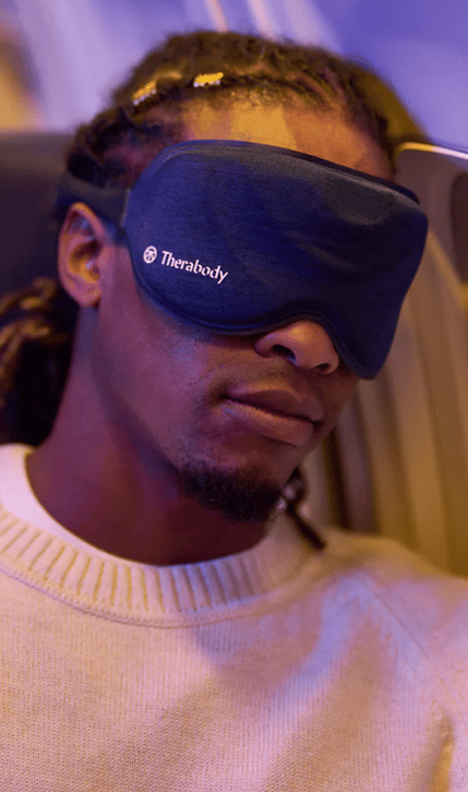 Man using Therabody SleepMask in airplane