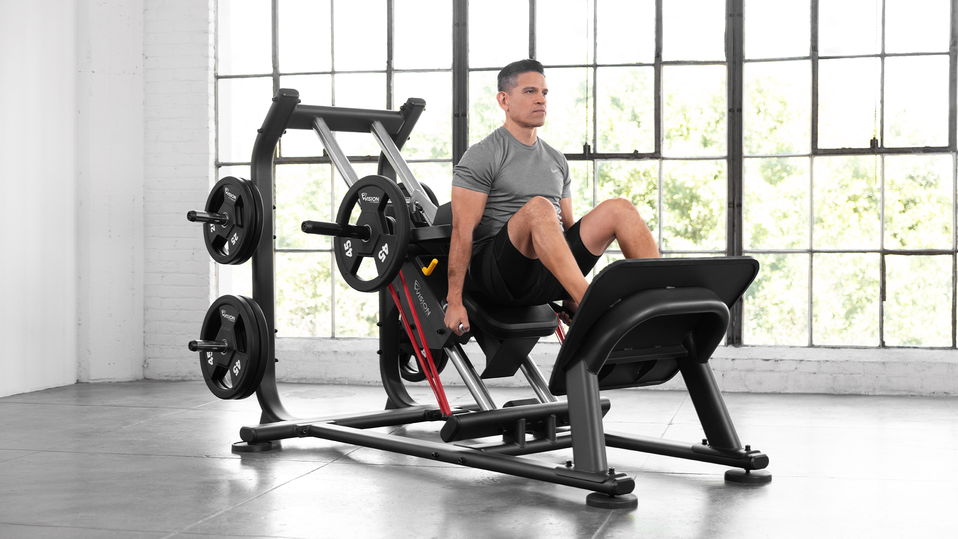 Male using Vision Hack Squat in small gym setting