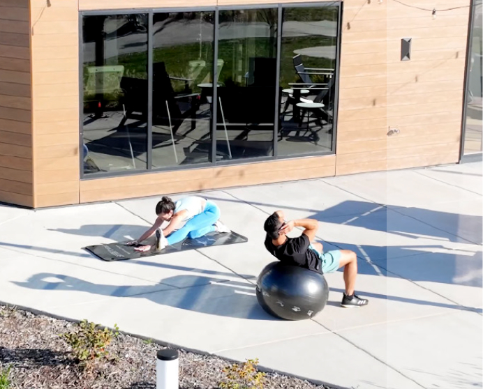 Two women performing yoga outside a multifamily facility