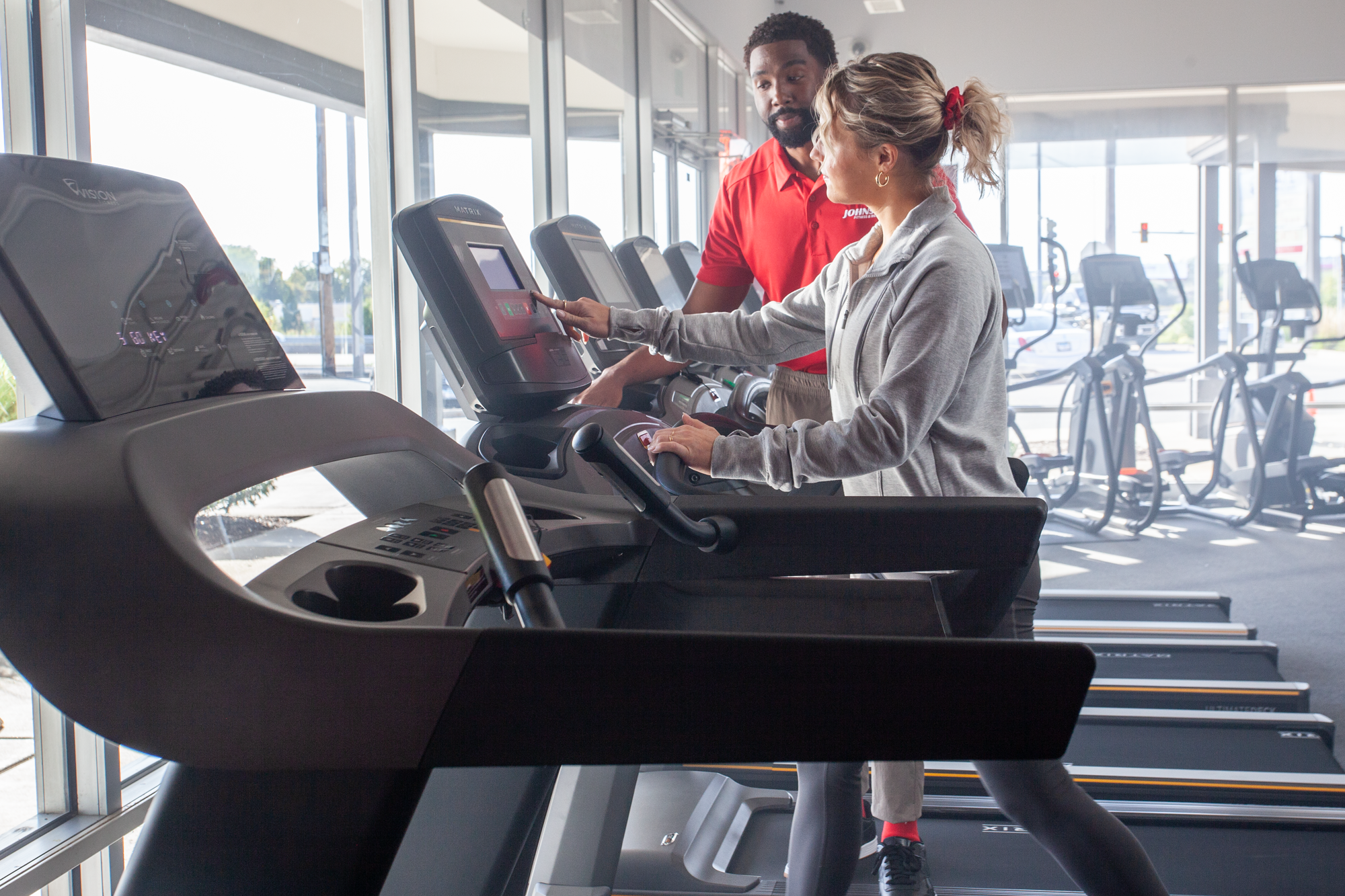 JFW team member with a woman trying a Matrix treadmill in store
