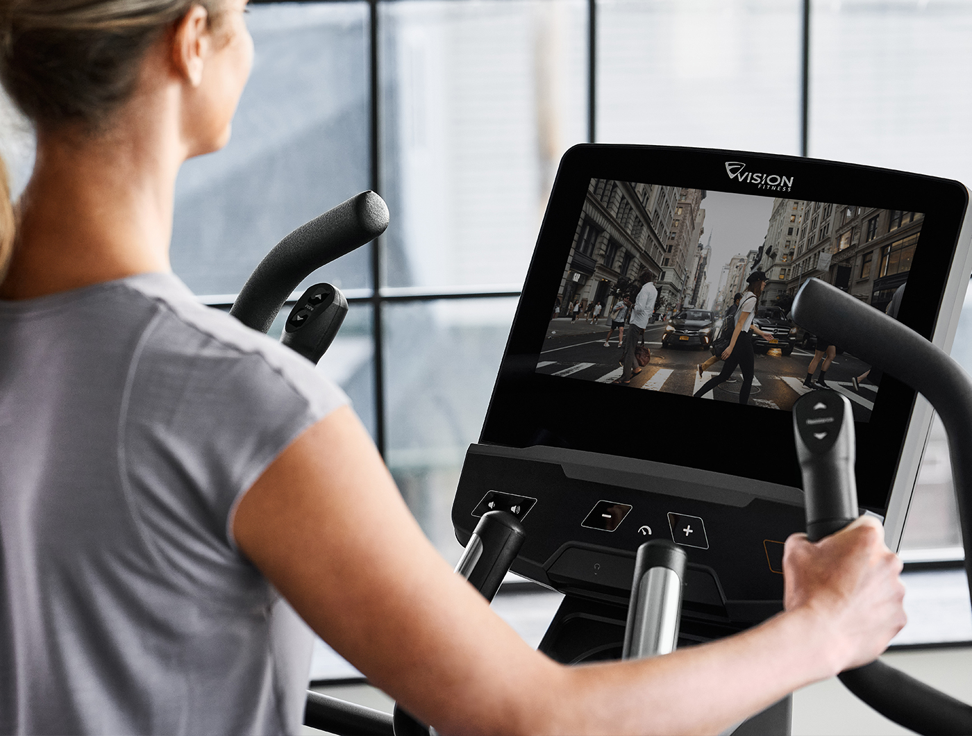 Woman working out on Vision commercial entertainment series elliptical trainer interacting with a city run course