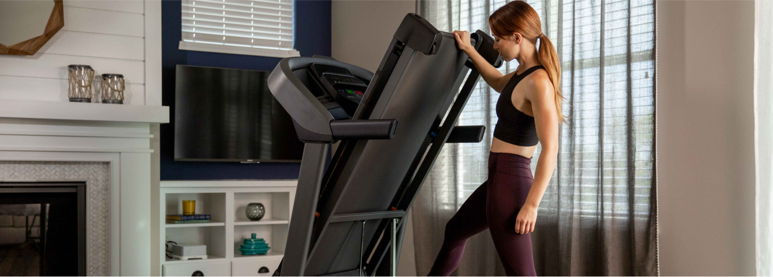 Woman folding a Horizon T101 treadmill in her family room