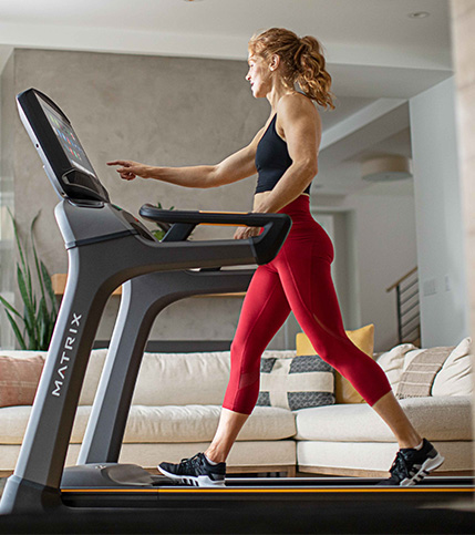 Woman walking on Matrix treadmill, selecting program on console