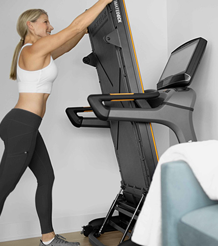 Woman storing a Matrix folding treadmill